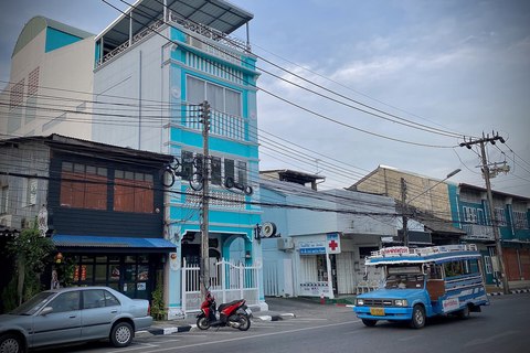 Songthaew azul circulando por una calle del casco antiguo de Phuket, junto a una casa de fachada turquesa