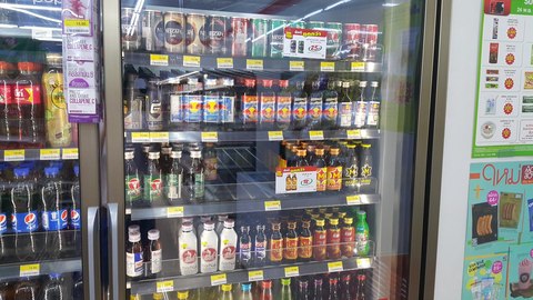 Nevera de una tienda de conveniencia tailandesa llena de botellas pequeñas de bebidas energéticas de distintas marcas